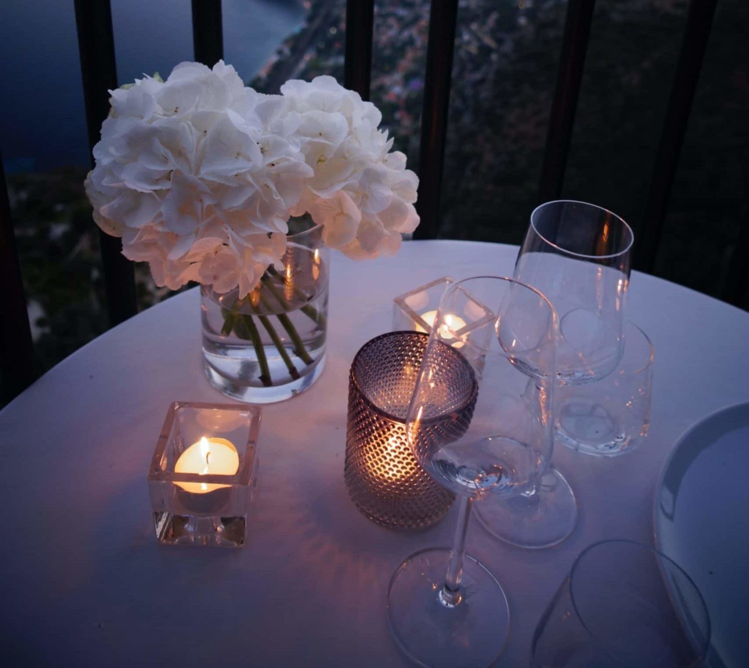 Dining table set with white flowers, glasses, and candles